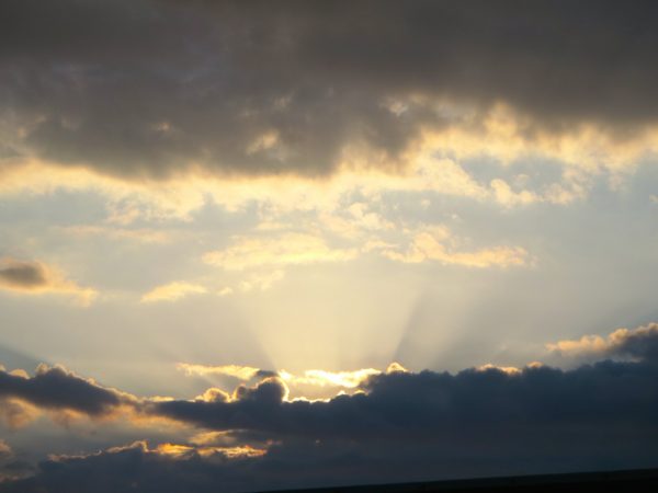 Sonnenstrahlen scheinen hinter dunklen Wolken hervor