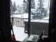 Ein dunkler Raum mit Tisch und aufgeklapptem Laptop und Schneetreiben hinter dem Fenster