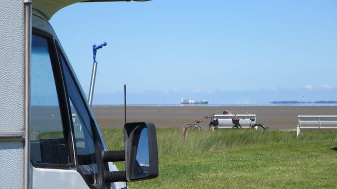 Ein Wohnmobil mit Blick auf eine Bank und dahinter die Nordsee bei Ebbe