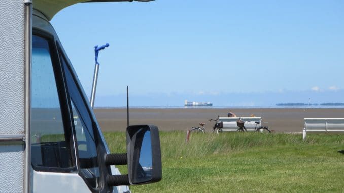 butjadingen-burhave-wohnmobilstellplatz Ein Wohnmobil mit Blick auf eine Bank und dahinter die Nordsee bei Ebbe
