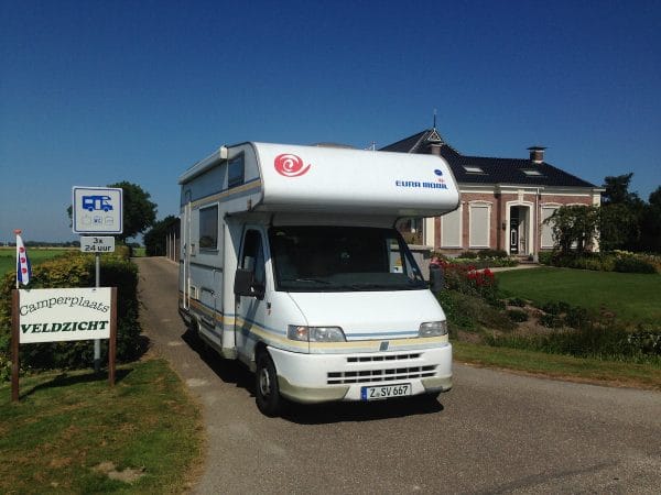 Wohnmobil vor einer Einfahrt und einem Bauernhaus