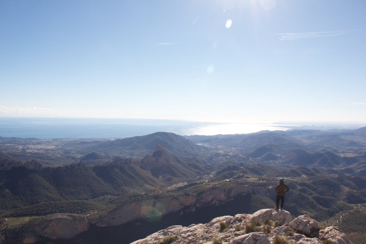 Blick über Berge auf das Meer und die Sonne.