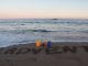 Im Hintergrund das Meer, im Vordergrund 4 Kerzen und in den Sand geschrieben "1. Advent"