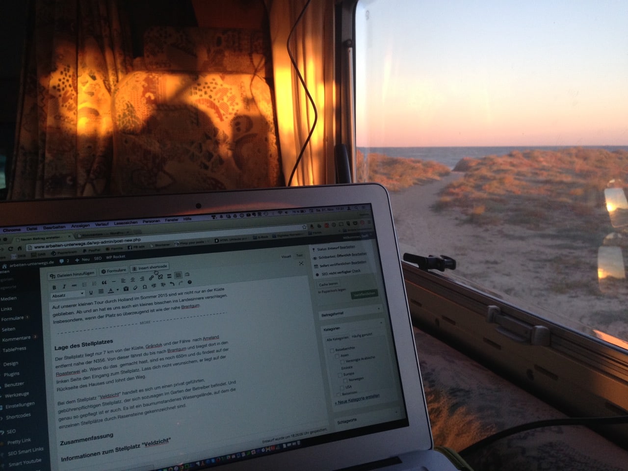 Ein Laptop steht vor einem Fenster, aus dem man das Meer sehen kann