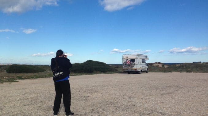 les-gavines-parkplatz Ein Mann fotografiert ein Wohnmobil, das einsam auf einem Parkplatz am Meer steht