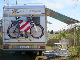 Ein Wohnmobil mit ausgefahrener Markise darunter Stühle