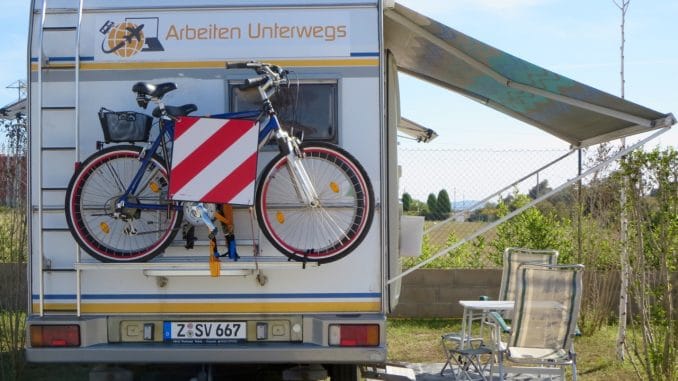 Ein Wohnmobil mit ausgefahrener Markise darunter Stühle