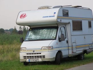 Ein Wohnmobil steht an einer Wiese im Grünen