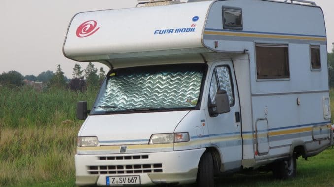 Ein Wohnmobil steht an einer Wiese im Grünen