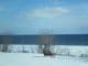 Eine einsame Bank auf einer schneebedeckten Wiese vor einem See