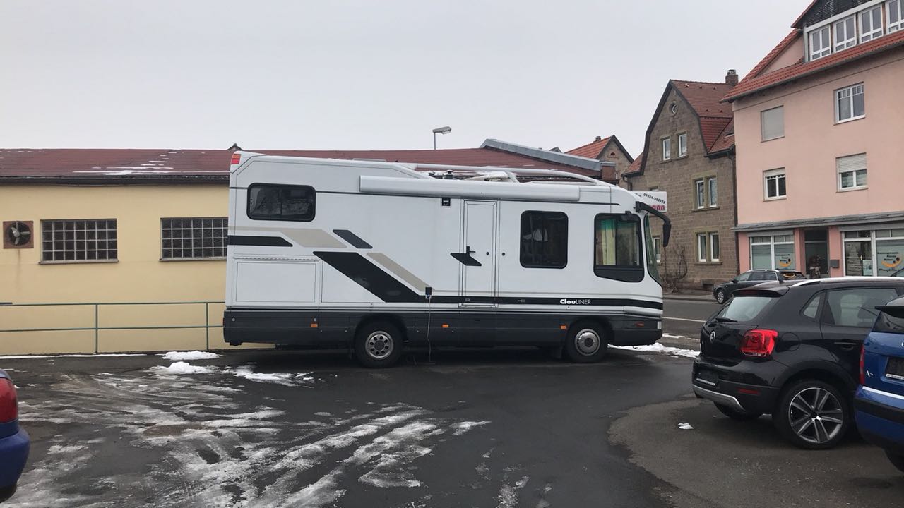 Ein ClouLINER steht auf einem Parkplatz vor einem Gebäude